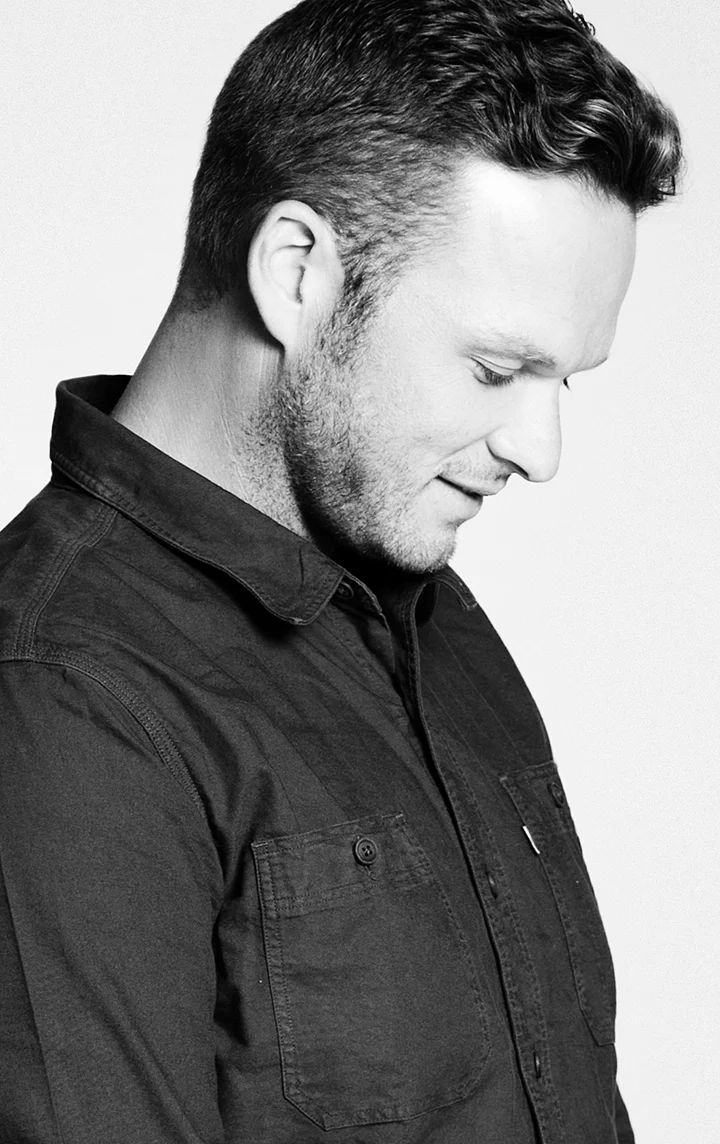 Alex Byrne in a dark work shirt, looking down.